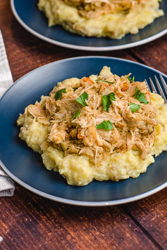 crockpot chicken and stuffing loaded onto a pile of mashed potatoes and garnished with parsley