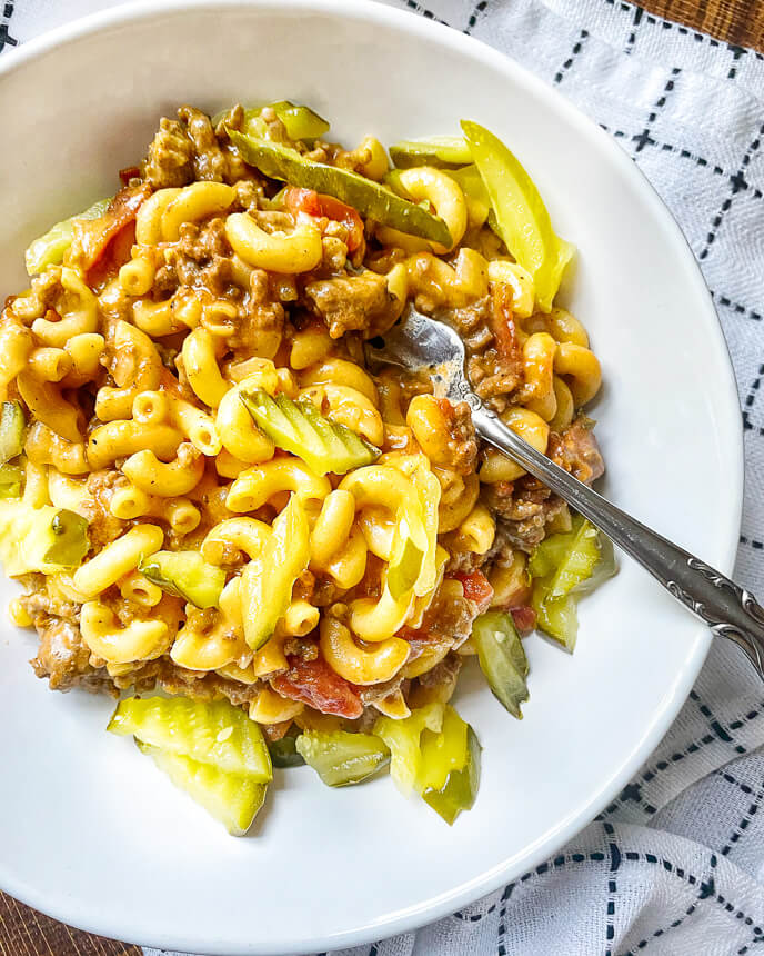 one pot cheeseburger pasta with pickles in a big white bowl
