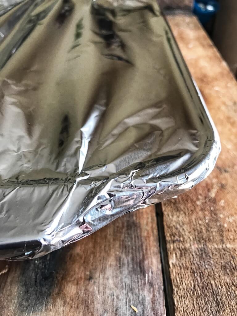 casserole dish being covered with foil 