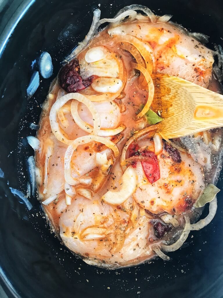 uncooked chicken breast in broth, citrus juice, sliced onions in a slow cooker