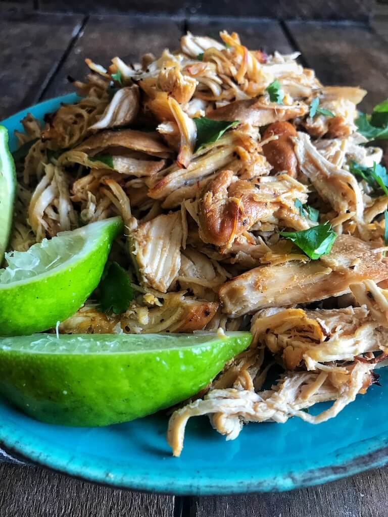 Slow Cooker Chicken Carnitas on a blue plate with fresh lime wedges 
