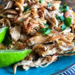 Slow Cooker Chicken Carnitas on a bright blue plate with a lime wedge