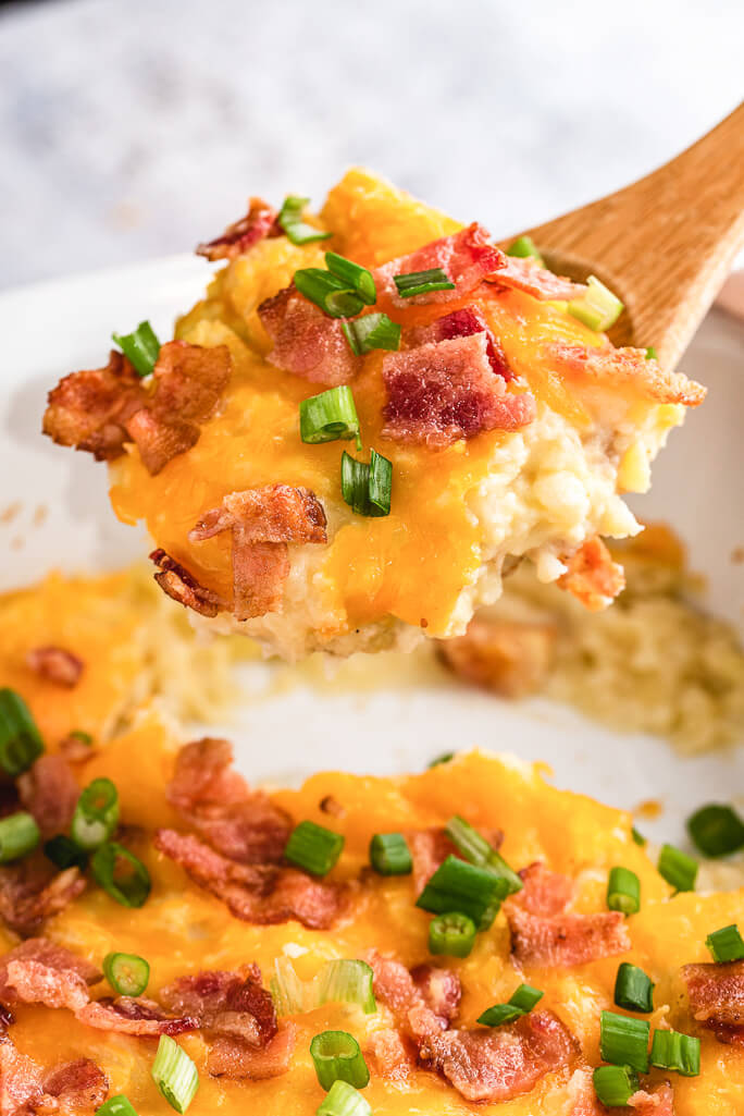 Loaded Cauliflower & Potato Bake being scooped out of a casserole dish