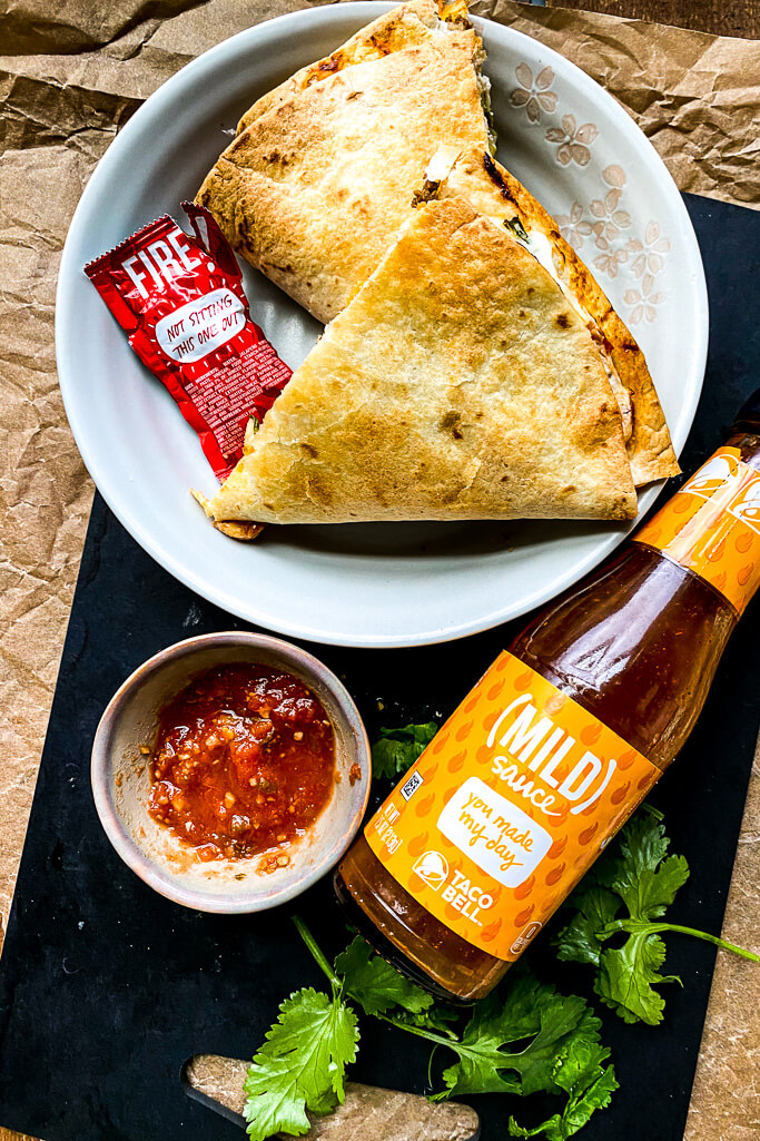 taco crunchwrap with salsa and bottle of taco sauce