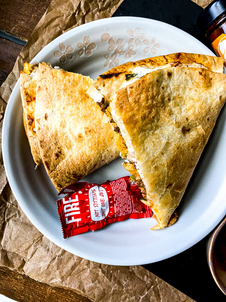 taco crunchwrap on a plate with a taco sauce packet