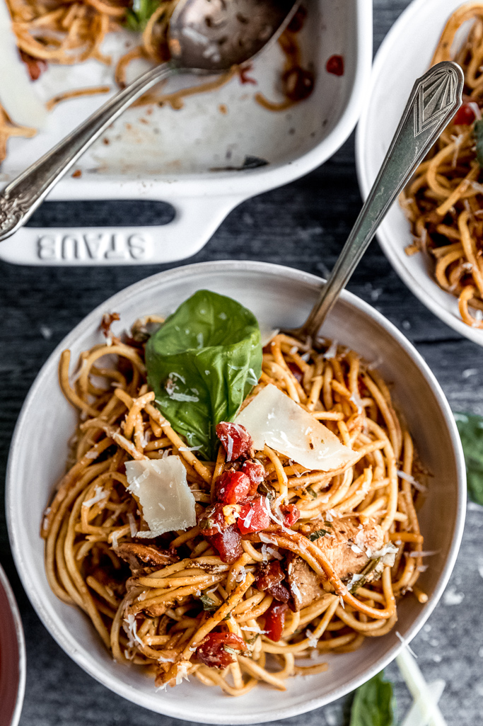white bowl filled with bruschetta chicken spaghetti with basil and spoon