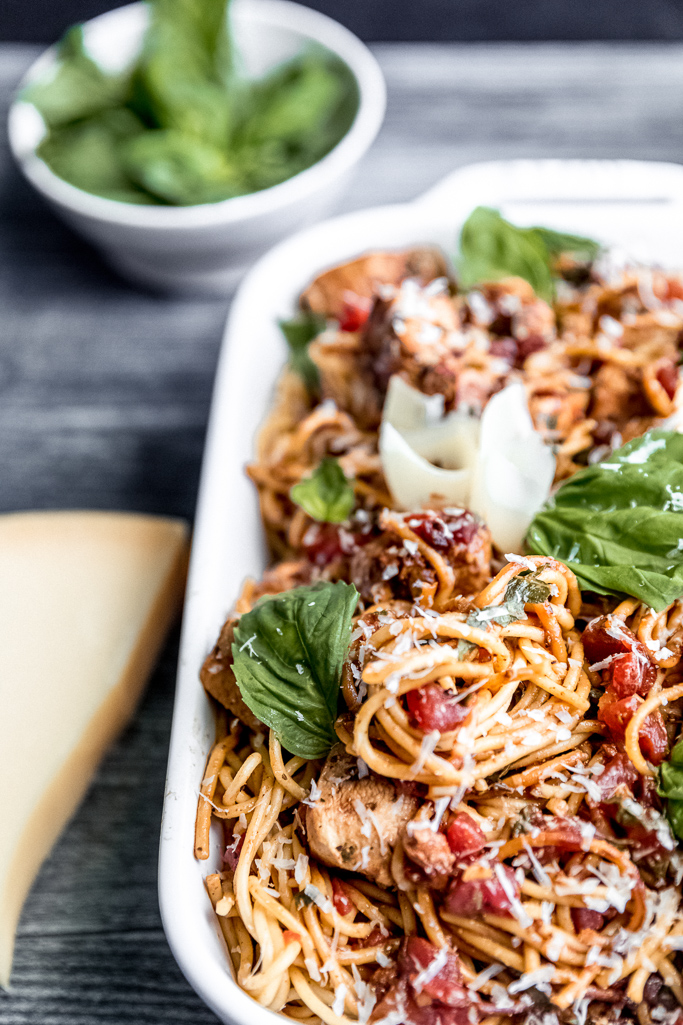 spaghetti, shaved parmesan, basil in a white dish