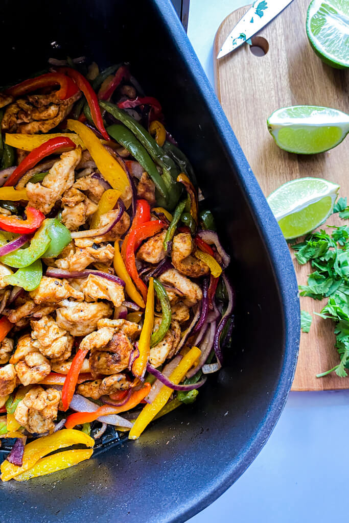 cooked chicken fajitas in air fryer plus lime and cilantro one the side on a wooden cutting board 