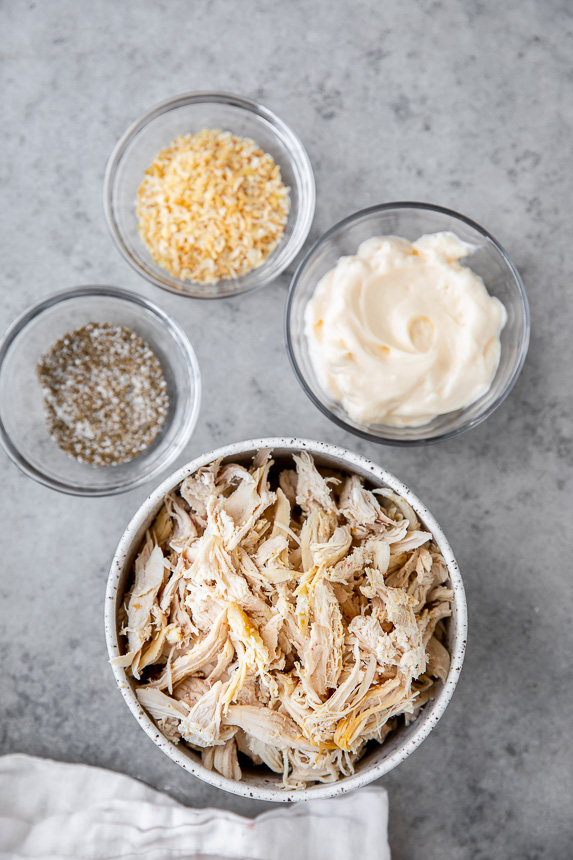 ingredients in bowls dried minced onion, Mayonnaise, celery salt, and shredded chicken