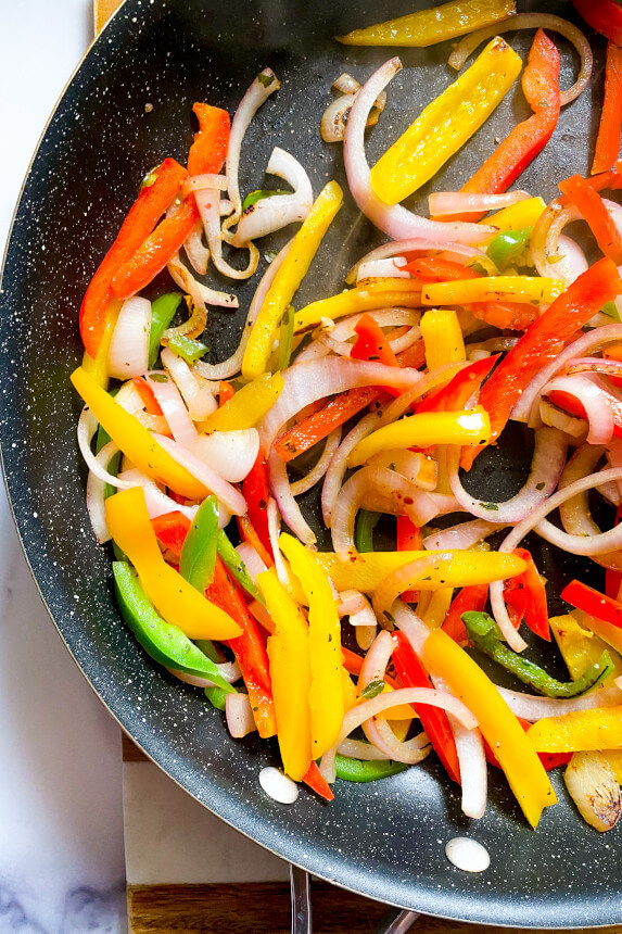 sliced bell peppers cooking in a skillet