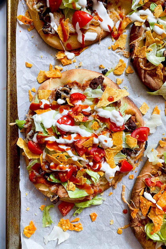 homemade taco pizza on sheet pan drizzled with sour cream and taco sauce