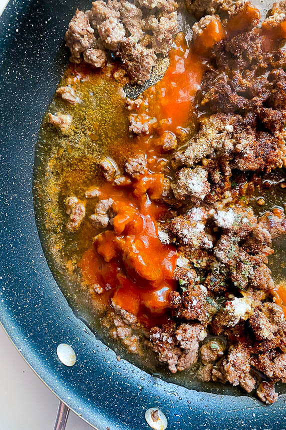 cooking ground beef with taco seasoning and taco sauce in skillet