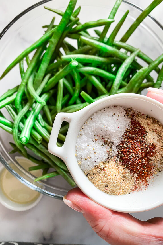 small dish of spices with a big bowl of raw green beans