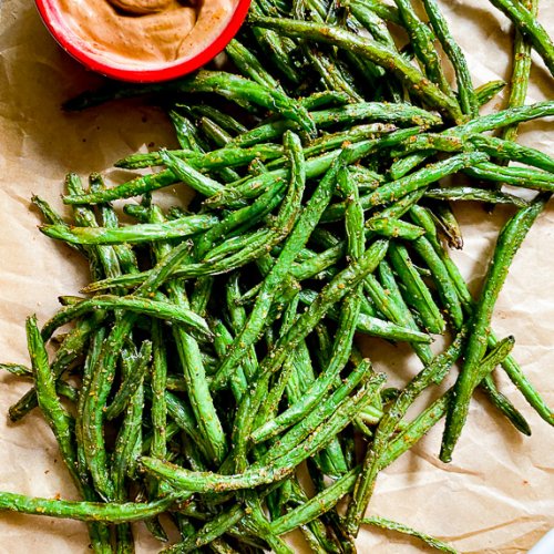 green beans on parchment paper with a small red bowl filled with dipping sauce