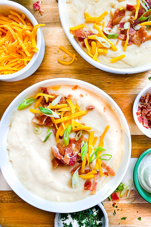 potato soup with toppings on the sides: shredded cheese, parsley, bacon, sour cream