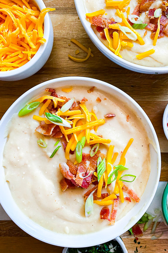 bowl of instant pot potato soup with cheese, crumbled bacon, and green onion on top