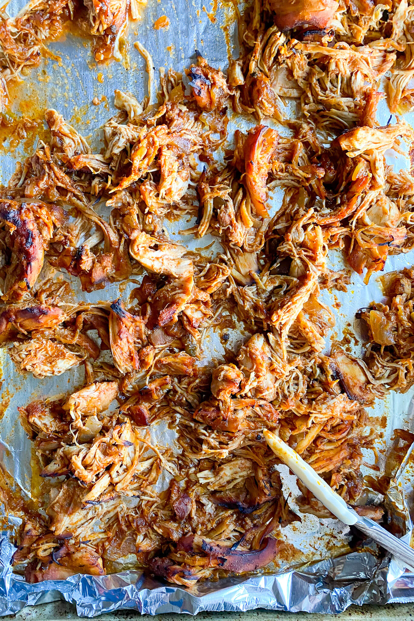 shredded chicken thats on a sheet pan that has been broiled in the oven
