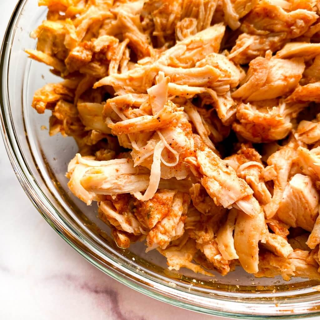 cooked and shredded chicken in a glass bowl