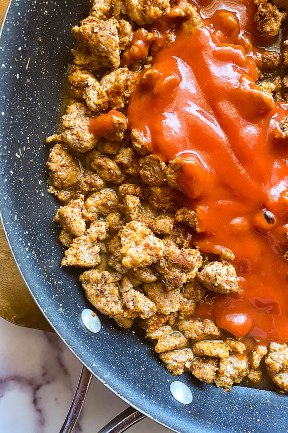 cooked and seasoned ground turkey in pan with tomato sauce on top