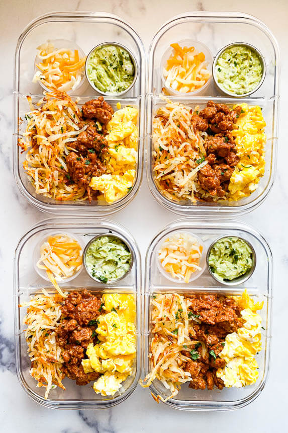 four meal prep containers filled with breakfast burrito bowls