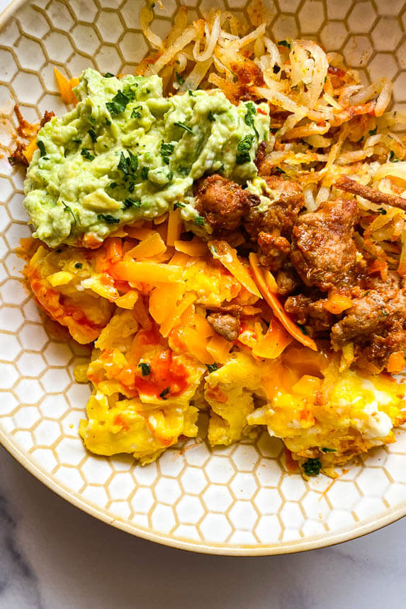 bowl with crispy hash browns, turkey taco meat, scrambled eggs, and guacamole dip 