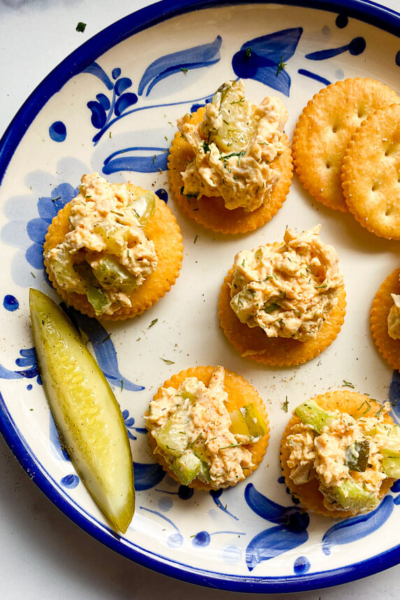 plate with ritz crackers and shredded chicken with pickles and celery in it and a pickle on the side