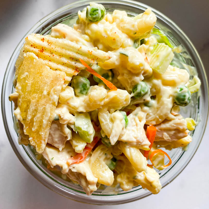 bowl with macaroni noodles, diced chicken breast, peas, celery, and shredded carrots. 