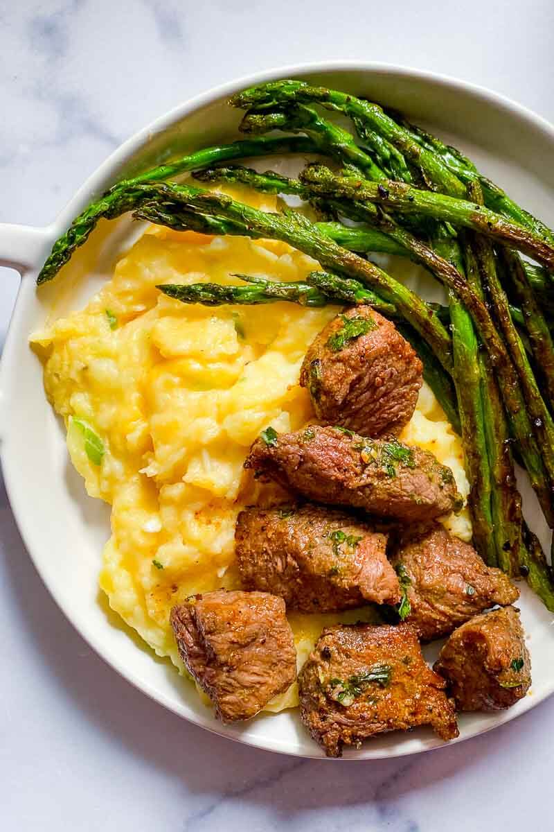 plate with steak bites, asparagus, and cheese mashed potatoes