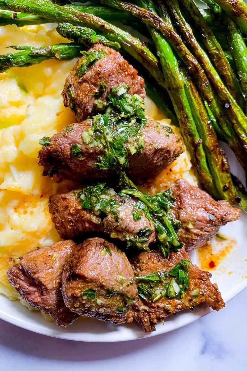 plate with steak bites, roasted asparagus, mashed potatoes, and chimchurri
