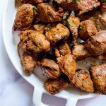 steak bites on a plate with parsley on top