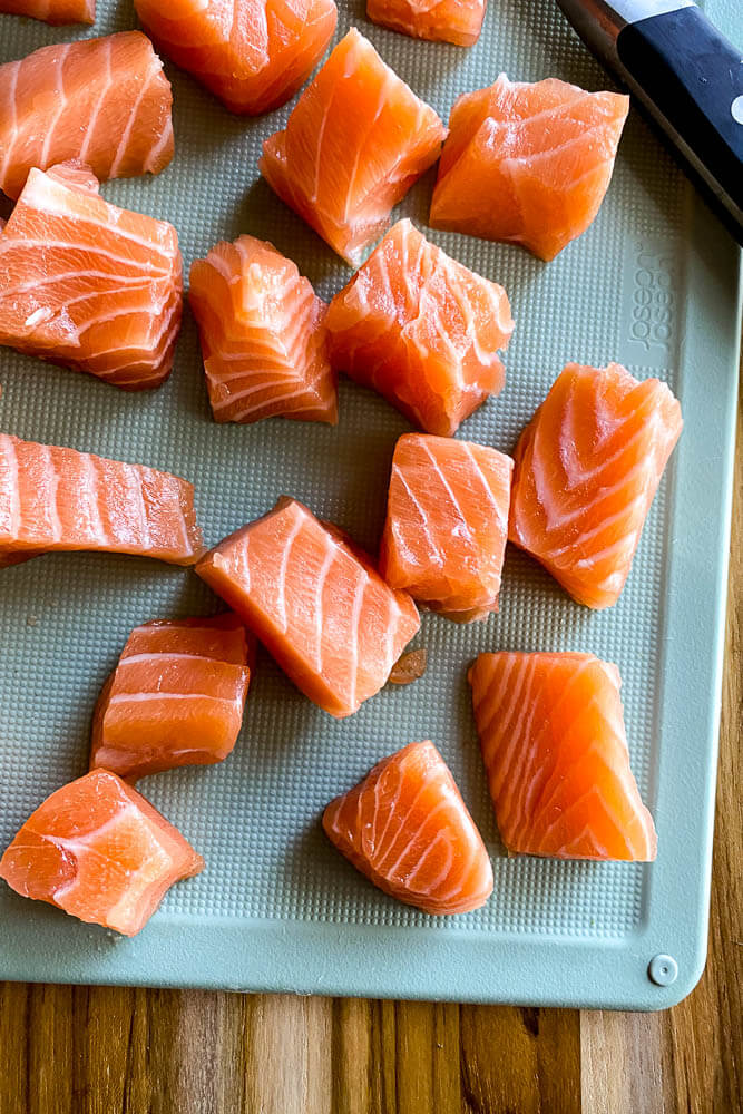 raw salmon cubes on cutting board