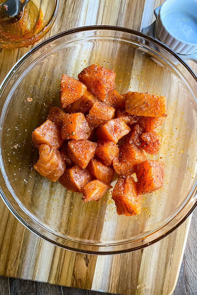 raw salmon cubes coated in spice rub in a bowl