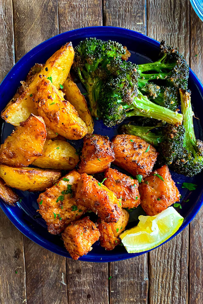 plate with salmon bites, broccoli, and potato wedges 