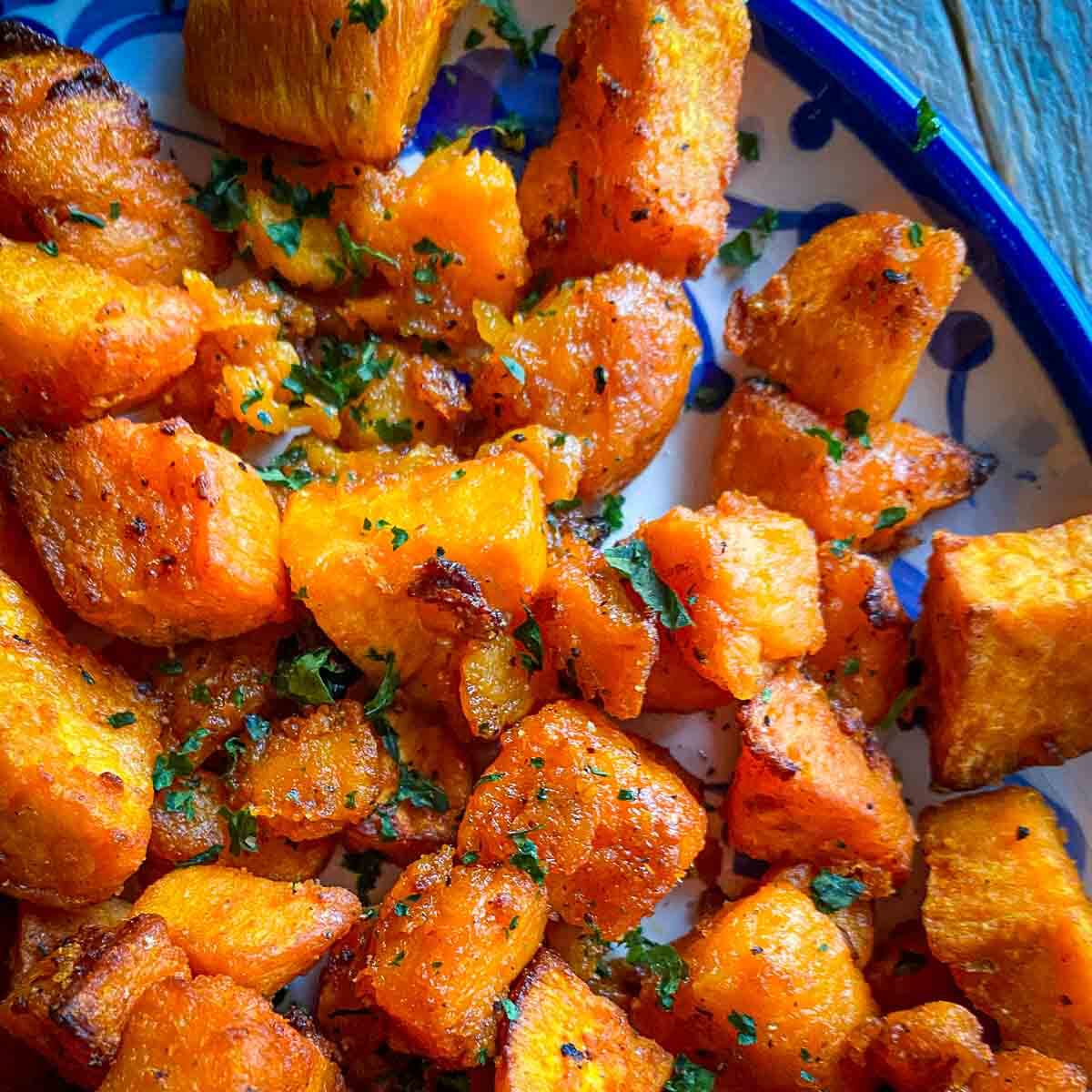 bright orange sweet potatoes with specks of green cilantro on blue and white plate