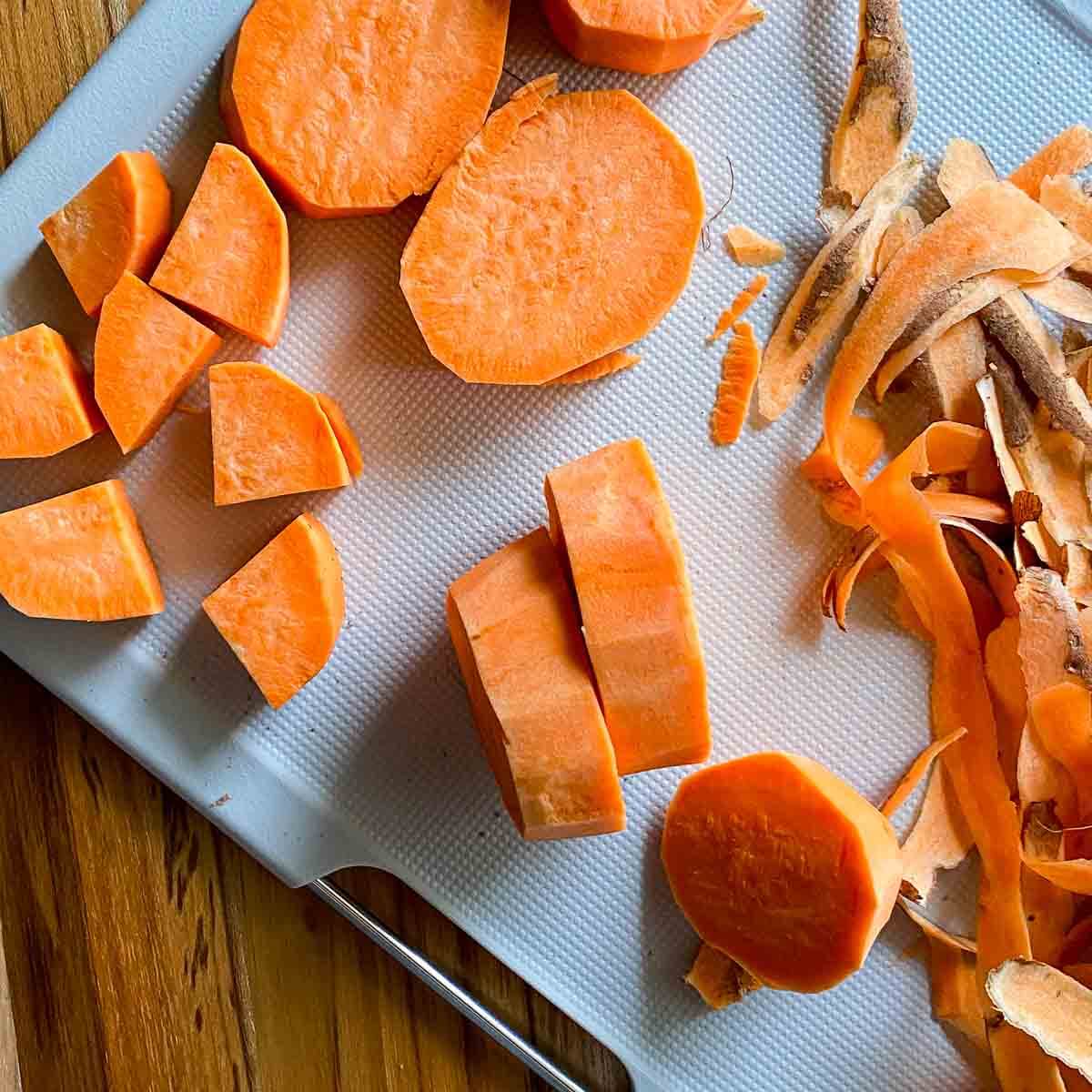 cutting board with bright orange sweet potatoes cut into different shapes 