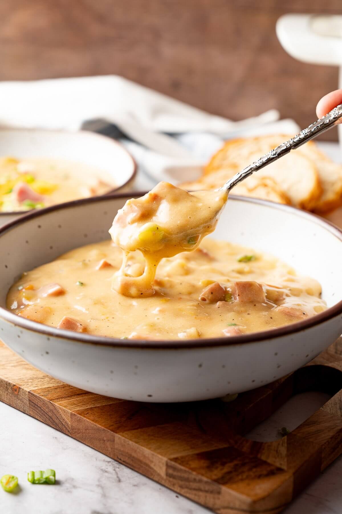spoonful of ham and potato soup being taken out of white bowl