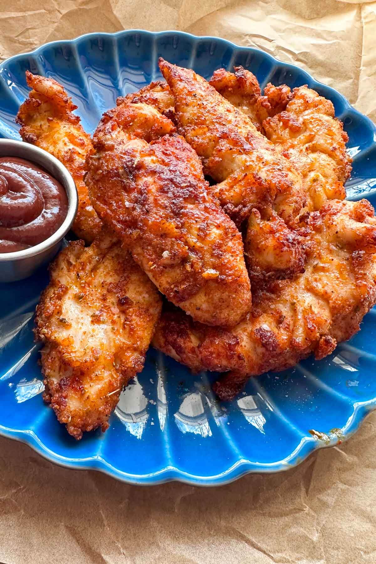 air fryer chicken tenderloins on a blue plate with a small container of bbq sauce on the side