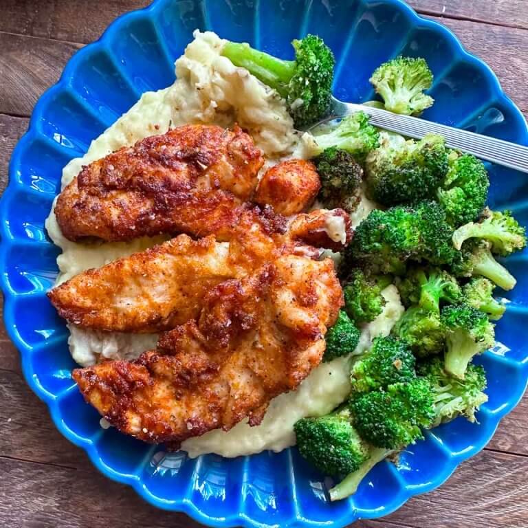 Air fryer chicken tenderloins served with creamy mashed potatoes and roasted broccoli on a blue plate