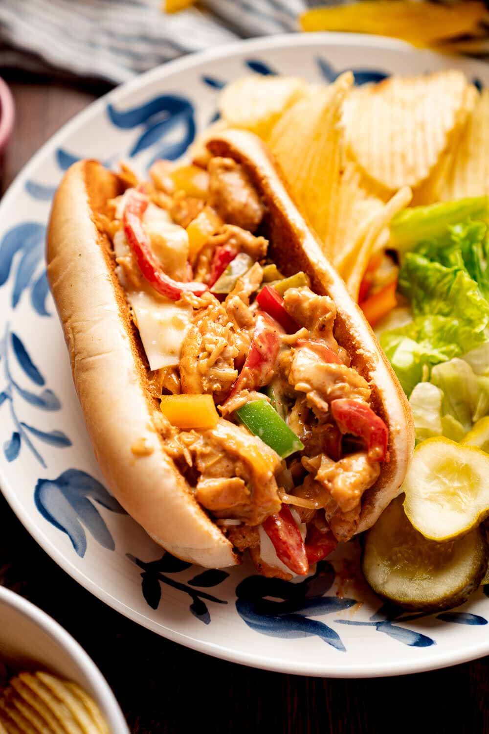 chicken cheesesteaks on plate with potato chips and salad