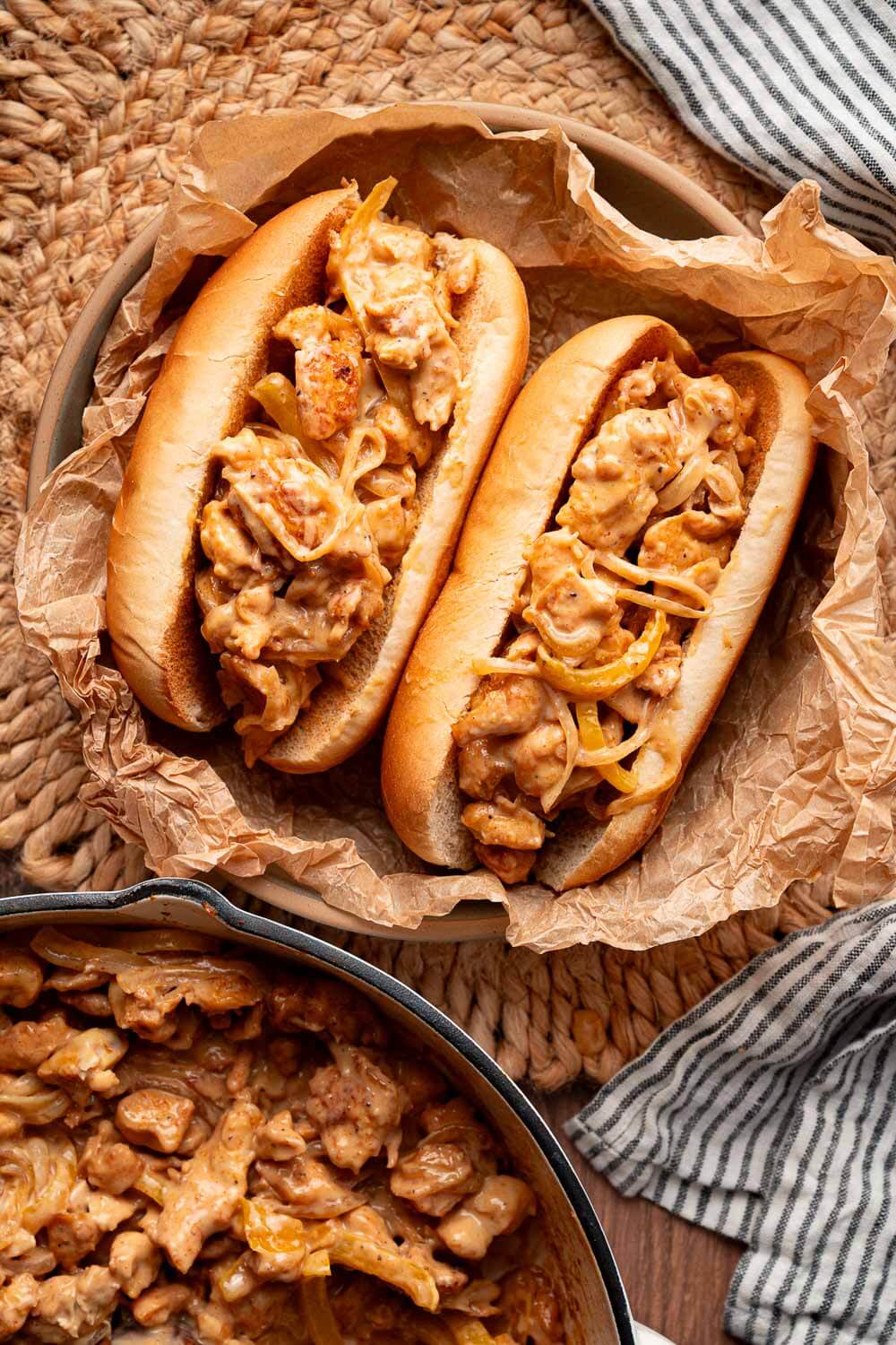 Two chicken cheesesteak sandwiches on toasted hoagie rolls served with cheesy chicken filling