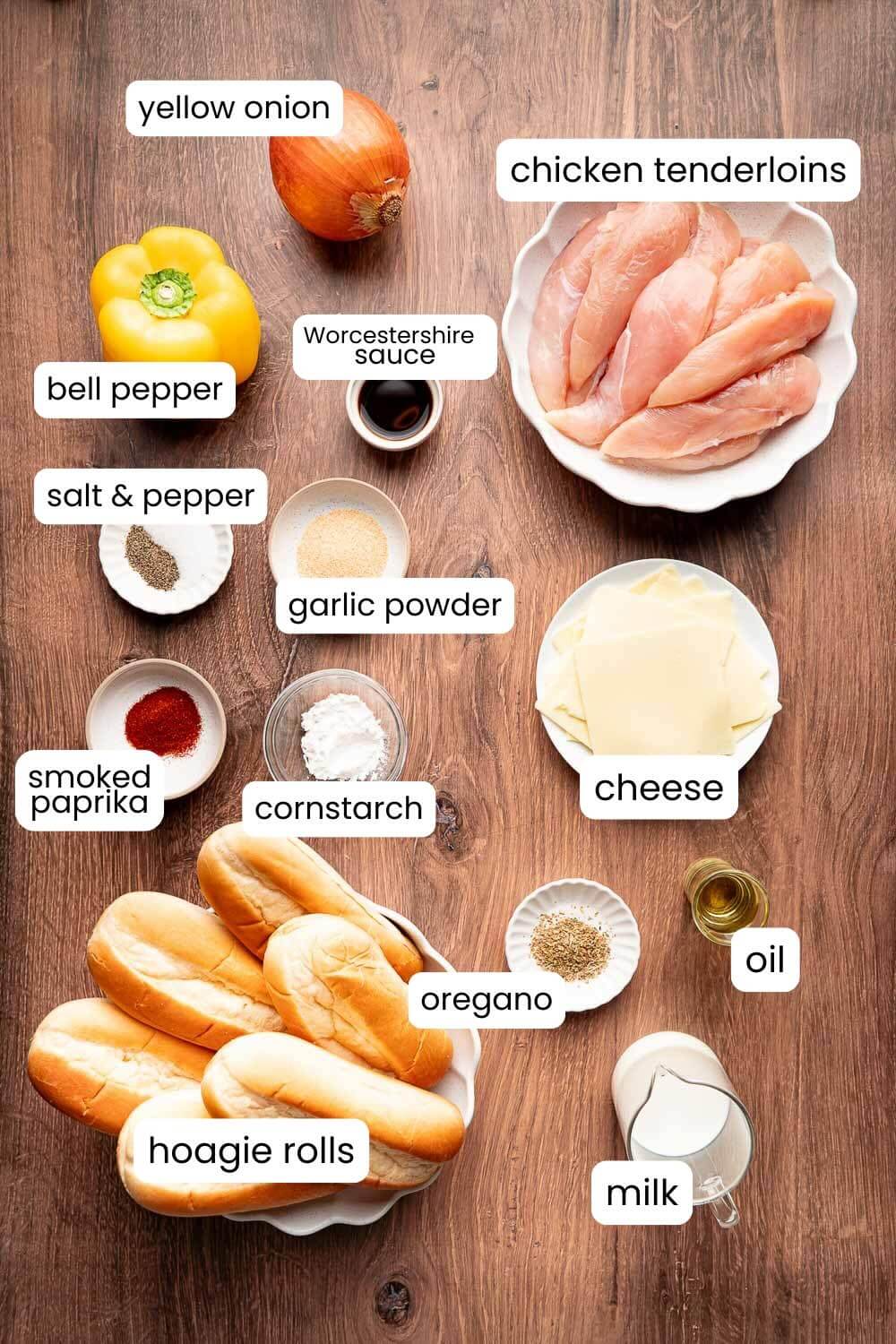 Ingredients for chicken cheesesteaks including chicken tenderloins, bell pepper, onion, hoagie rolls, cheese, and seasonings
