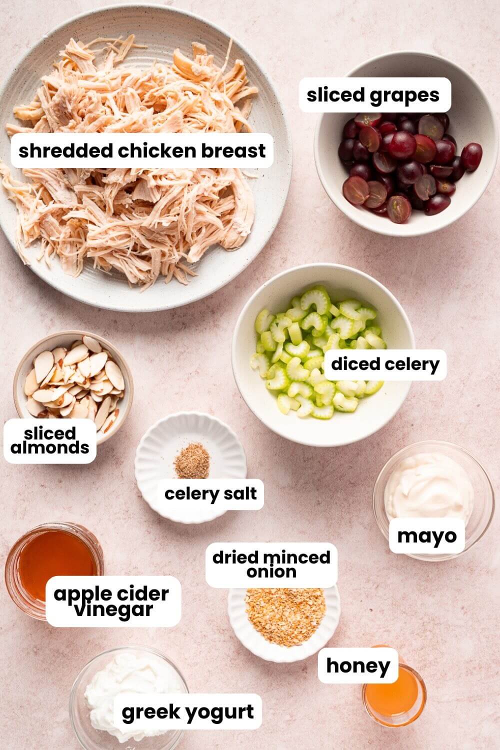 small bowls of ingredients: shredded chicken, sliced grapes, sliced almonds, diced celery, celery salt, apple cider vinegar, greek yogurt, honey. mayo, and minced onion