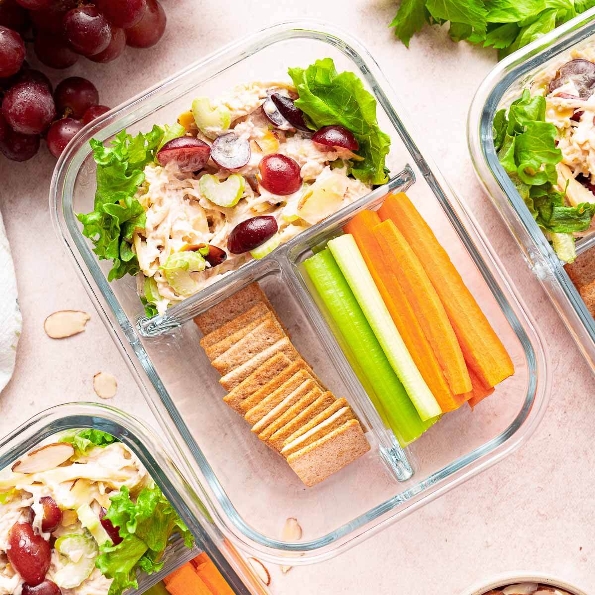 chicken salad with crackers, celery, and carrot sticks in container for meal prep.