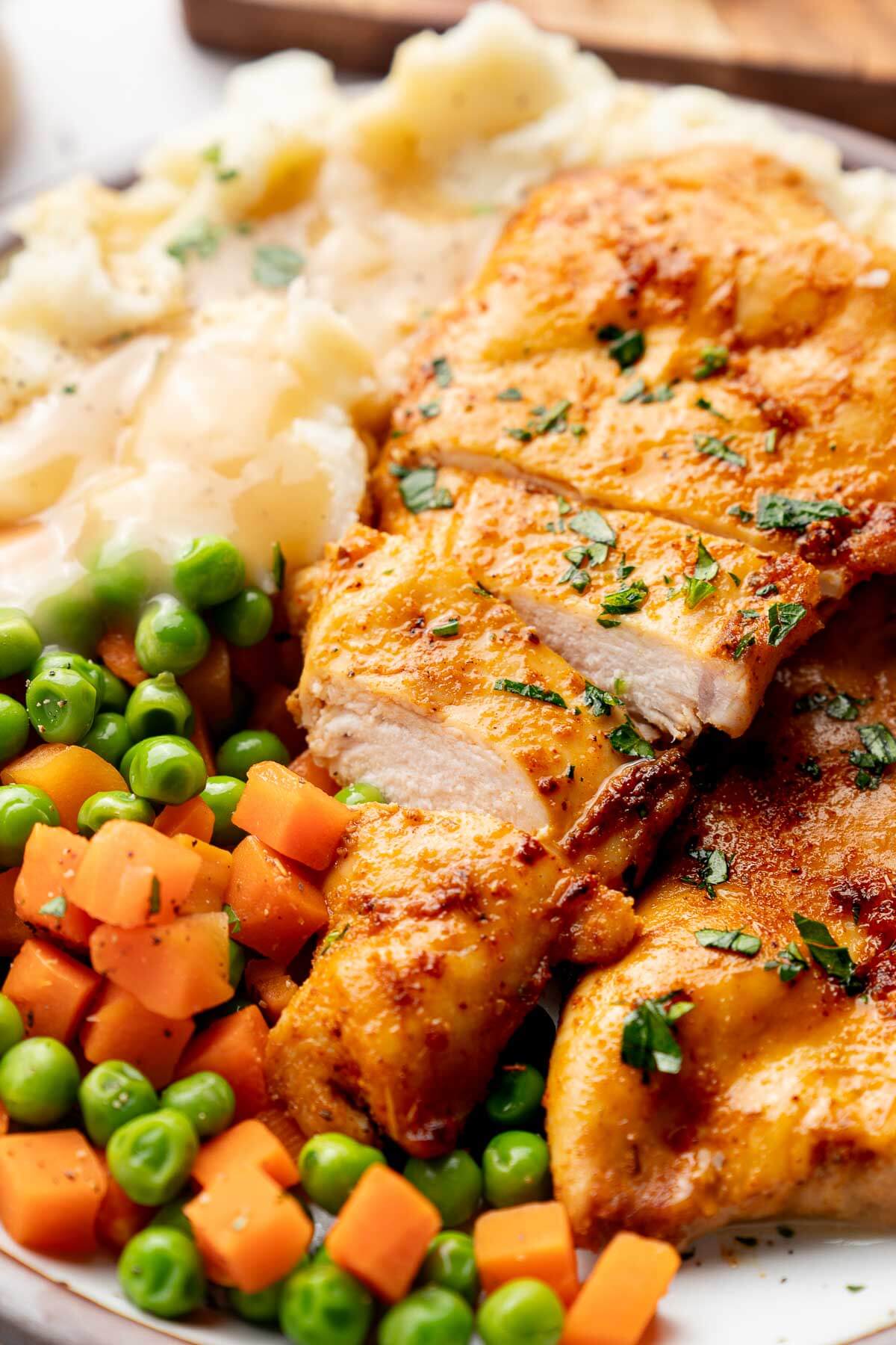 baked chicken breast with mashed potatoes, carrots, and peas