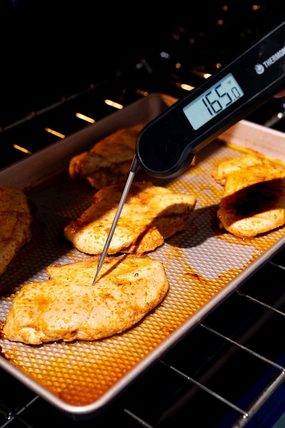 checking baked chicken breast temperature with a meat thermometer