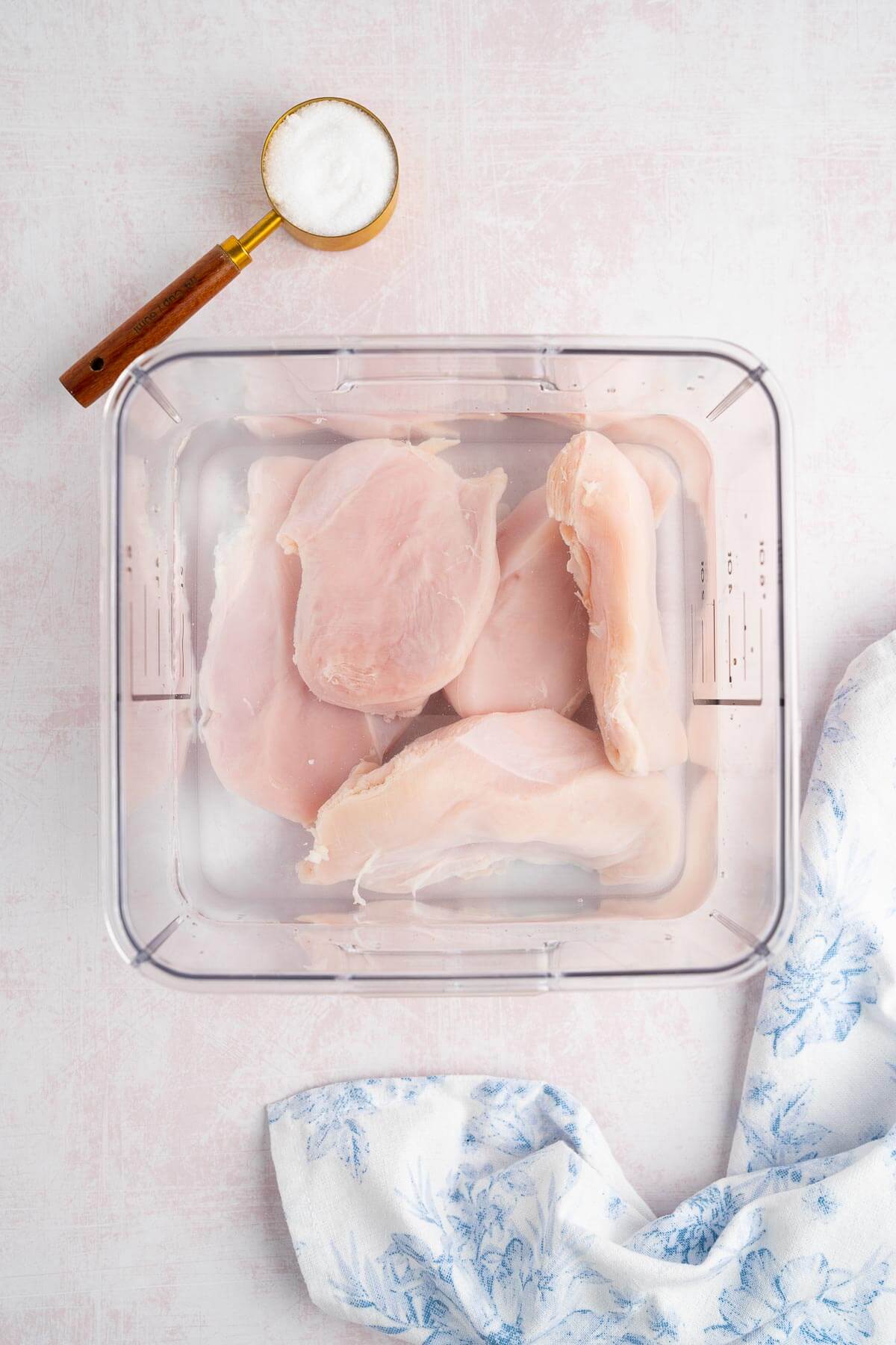 chicken breast brining in a container of water 