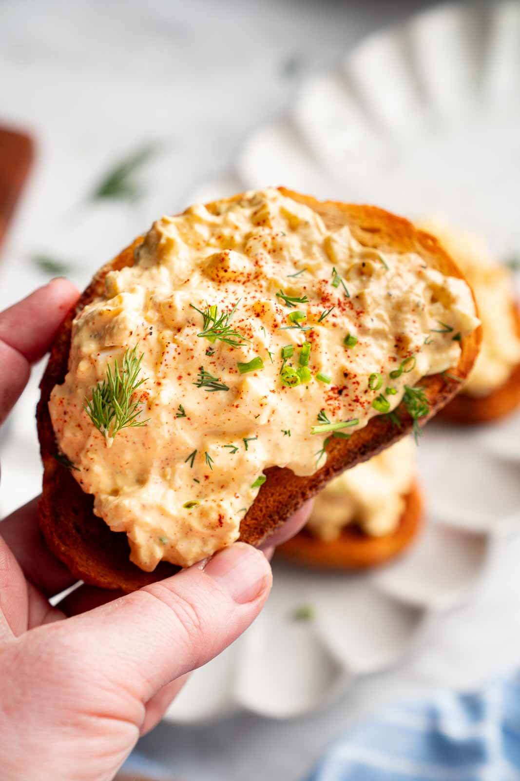 hand holding a slice of toast with cottage cheese egg salad on top