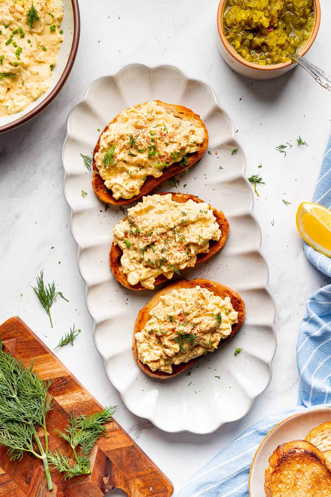 cottage cheese egg salad on toasts surrounded with fresh dill and lemon