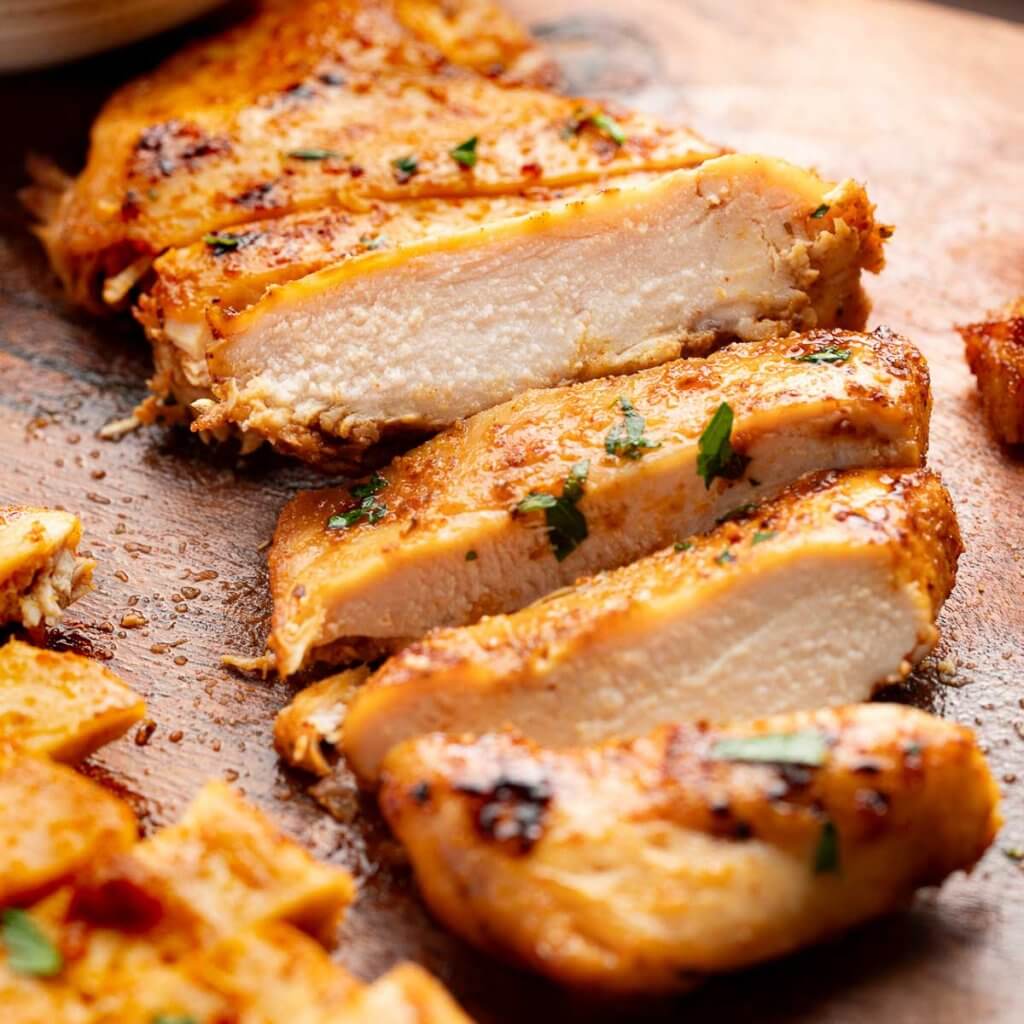 juicy easy baked chicken breast sliced on cutting board