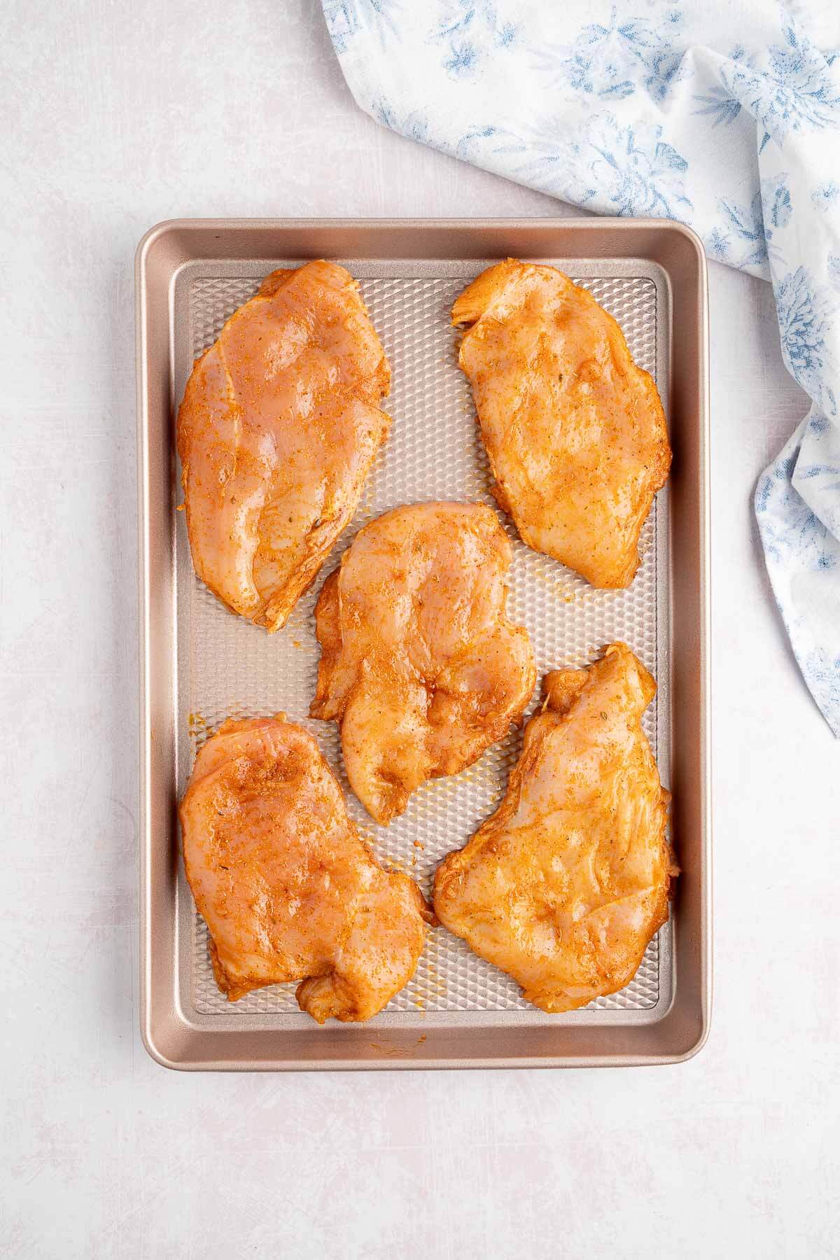 seasoned raw chicken breast on sheet pan